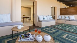 A modern living room with a sofa, a round coffee table, and a dining area in the background. - Rais house with private access to the sea (Solanto)