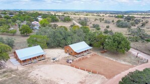 A rural property with two wooden cabins, a fenced riding arena, and surrounding trees. - Benjamin Cabin-HotTub-10 min to Main Street! (Fredericksburg)