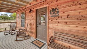 Eine Holzhütte mit Veranda, einer Tür mit Wappen und zwei Schaukelstühlen.