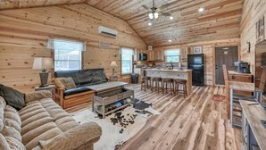 A log cabin interior with a living room, kitchen, and dining area. - Benjamin Cabin-HotTub-10 min to Main Street! (Fredericksburg)