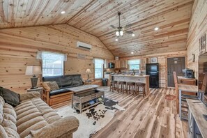 A log cabin interior with a living room, kitchen, and dining area. - Benjamin Cabin-HotTub-10 min to Main Street! (Fredericksburg)