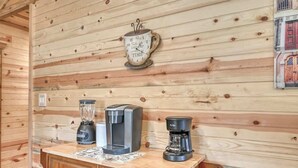 Ein Holzblockhaus im Inneren, mit einer Holzwand, einer Kaffeemaschine, einem Mixer und einer Uhr.