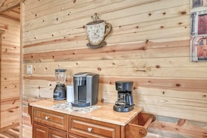 Ein Holzblockhaus im Inneren, mit einer Holzwand, einer Kaffeemaschine, einem Mixer und einer Uhr.