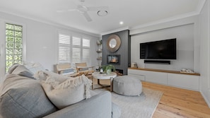 Un salon moderne avec un canapé, des fauteuils, un téléviseur et une cheminée.