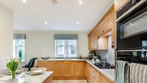 A modern kitchen with wooden cabinets, a central island, and a built-in oven. - Market Square is a cosy, well-equipped holiday home. (Grassington)