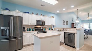 Una cocina moderna con armarios blancos, electrodomésticos de acero inoxidable y una isla central.