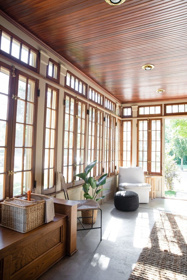 Relax in a spacious room with high ceilings, large windows, and a comfortable seating area.