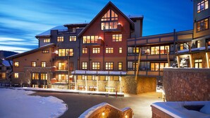 Ein mehrstöckiges Hotel mit Skiort-Architektur, ausgestattet mit Balkonen, großen Fenstern und einer Steinfassade.