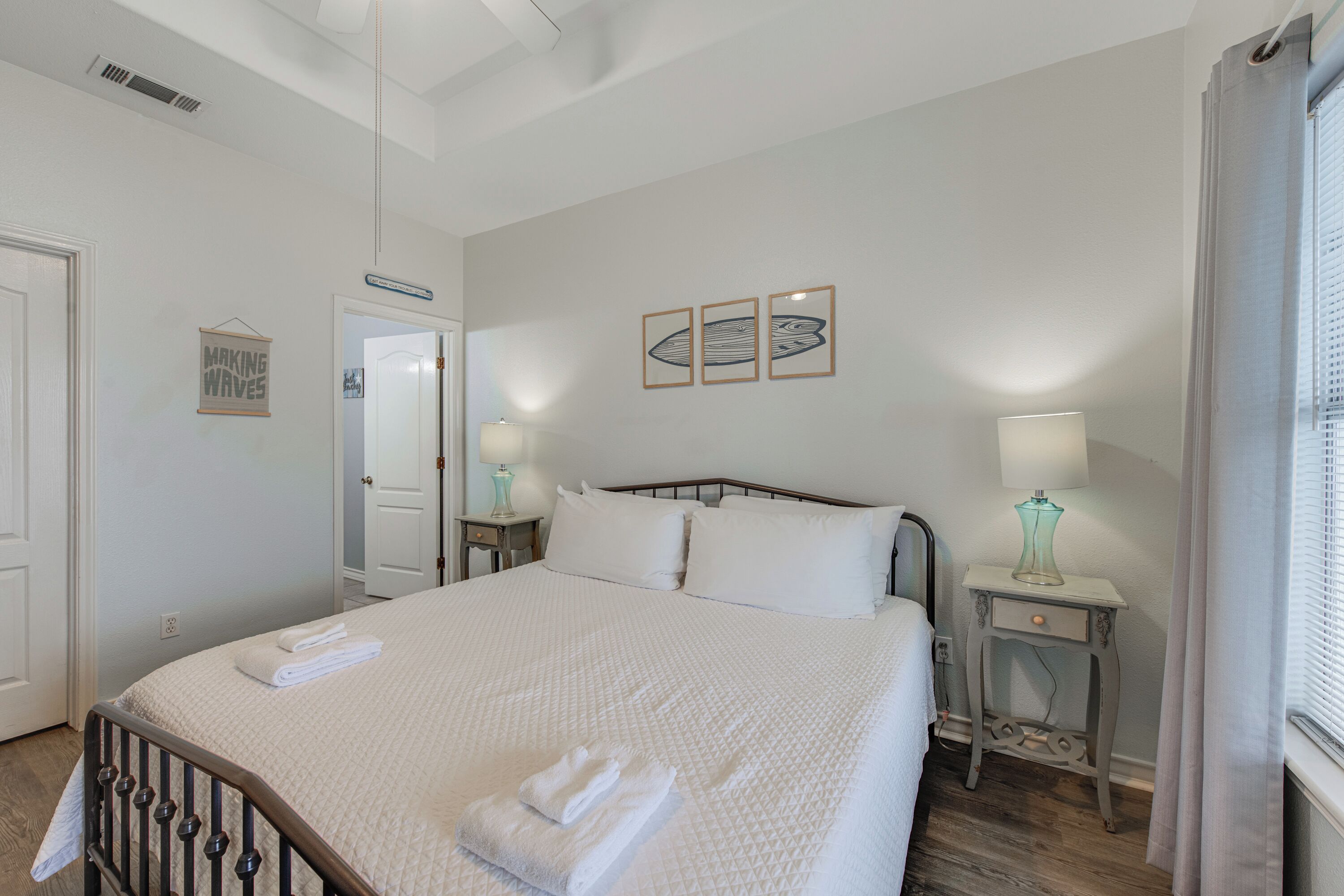 A neatly made bed with white bedding and two bedside tables with lamps.