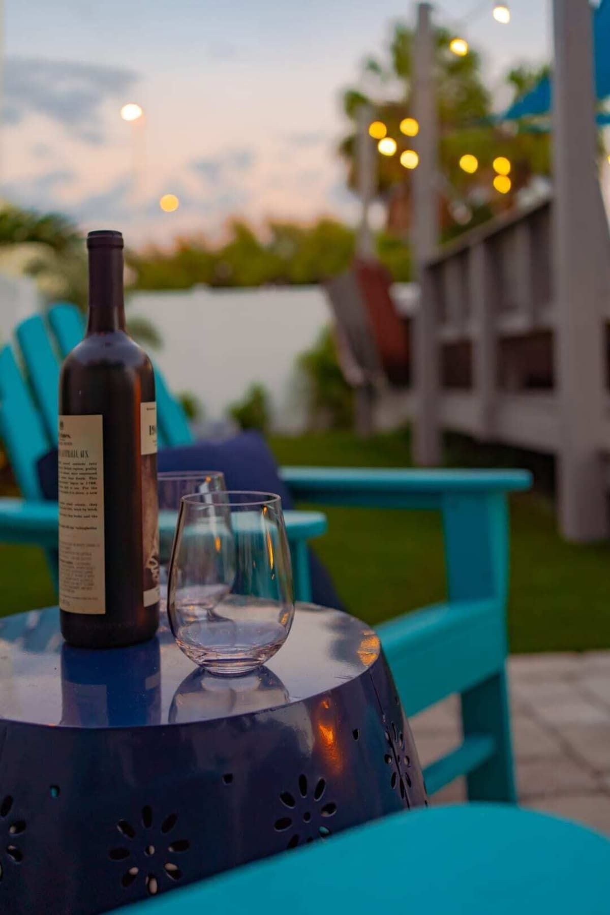 A bottle of wine and an empty glass on a table outdoors.