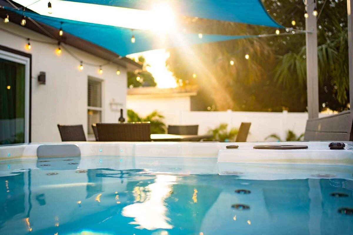 Een zwembad met een jacuzzi, omringd door tuinmeubilair en een overdekt gedeelte.