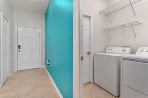 A laundry room with a white door, a washing machine, and a dryer.