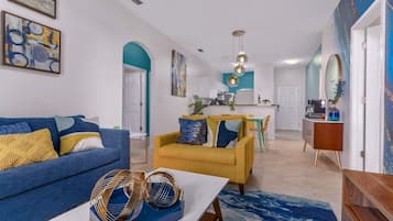 Un salon moderne avec un canapé bleu, un fauteuil jaune et une table basse.