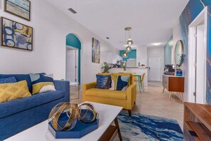 A modern living room with a blue sofa, a yellow armchair, and a coffee table.