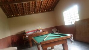 Relax in a spacious room with a pool table, comfortable seating area, and a sloped ceiling with exposed beams.