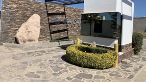A modern building with a stone facade, a large rock, and a well-maintained hedge. - COUNTRY HOUSE LAKE CHAPALA/JOCOTEPEC (JOCOTEPEC)