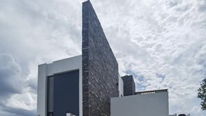 A modern house with a unique angular design, featuring a prominent stone facade and a large glass window. - COUNTRY HOUSE LAKE CHAPALA/JOCOTEPEC (JOCOTEPEC)