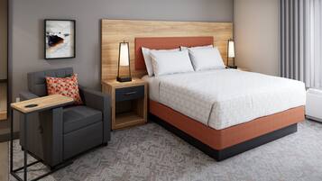 A hotel room with a bed, a chair, a nightstand, a lamp, and a picture on the wall.