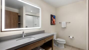 A modern bathroom with a large mirror, a sink, a toilet, and a towel rack.