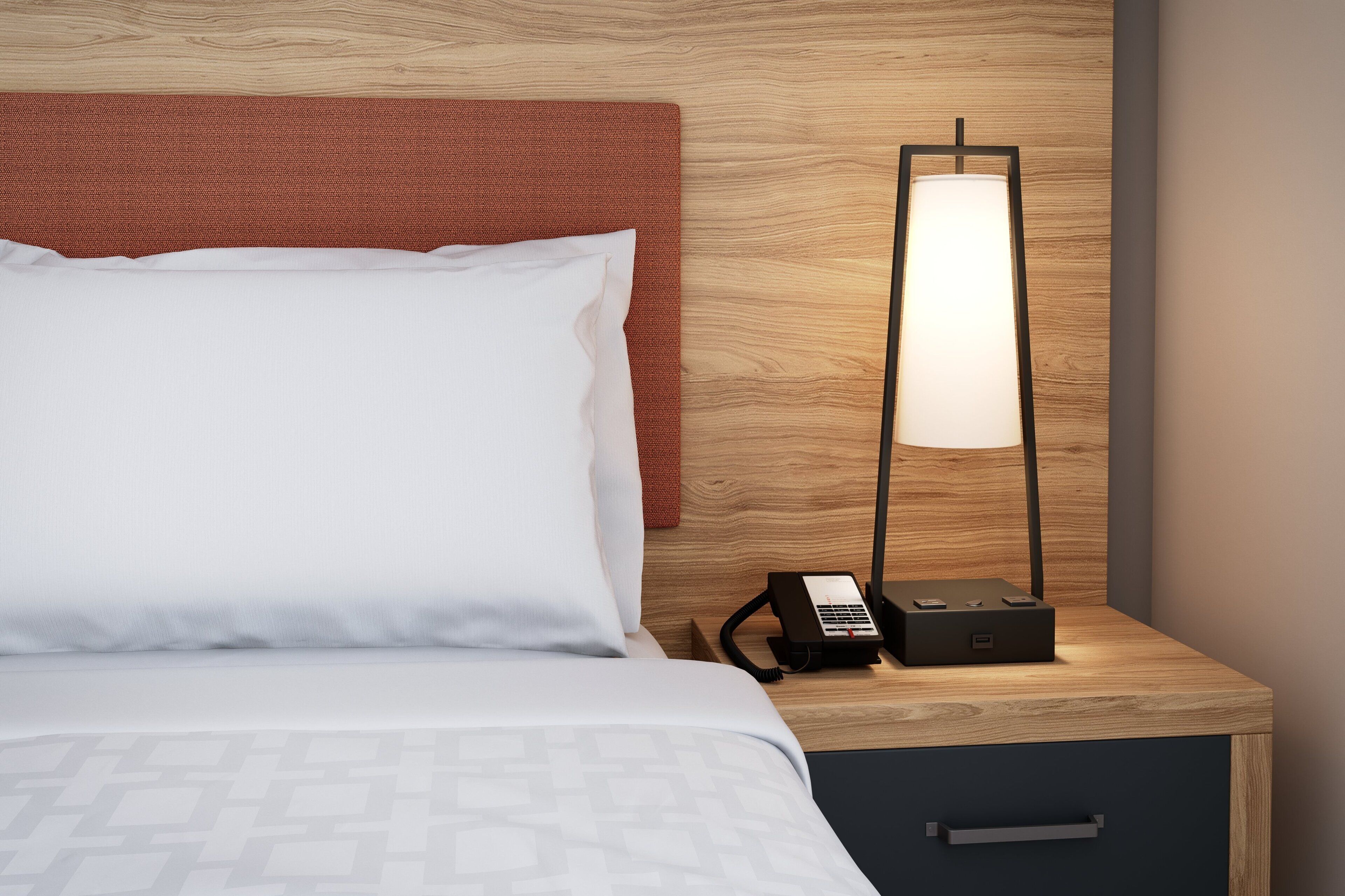 Una habitación de hotel con una cama, una mesita de noche, una lámpara y un teléfono.