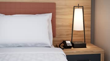 Una habitación de hotel con una cama, una mesita de noche, una lámpara y un teléfono.