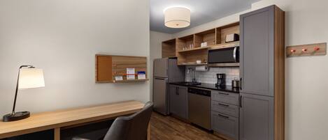 A modern kitchen with grey cabinets, a microwave, a refrigerator, and a wooden countertop.