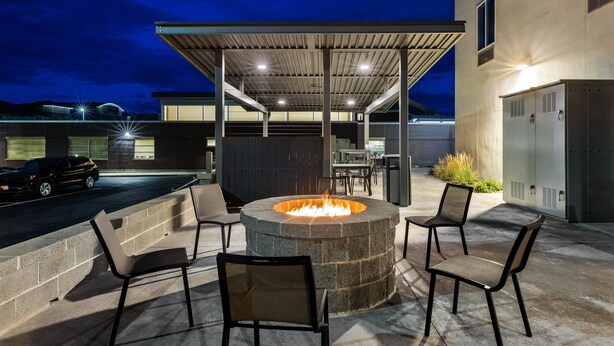 An outdoor patio with a stone fire pit, seating, and a covered area.