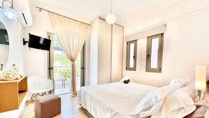 A hotel room with a bed, a desk, a chair, a TV, and a window with curtains. - Luxury Villa San George with private pool (Perigiali)