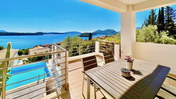 A balcony with a pool, outdoor furniture, and a view of the sea and mountains. - Luxury Villa San George with private pool (Perigiali)