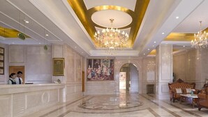 A hotel lobby with a reception desk, a chandelier, and a seating area. - Vienna International Hotel (Foshan)
