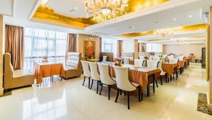 A hotel dining area with a long table, multiple chairs, and a chandelier. - Vienna International Hotel (Foshan)