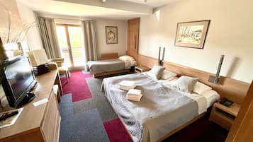 Habitación de hotel con dos camas, televisión, escritorio y ventana con cortinas.