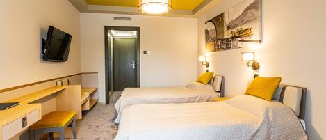 A hotel room with two beds, a desk, a chair, a television, and a painting on the wall.