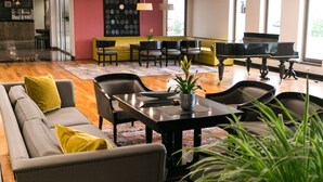 Un moderno vestíbulo de hotel con un piano, zona de estar y una mesa de comedor.
