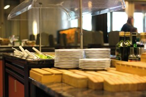 Un buffet avec des piles d’assiettes et une variété de plats présentés sous une cloche de verre.