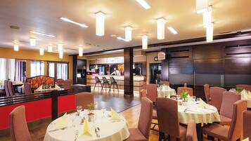 A restaurant with round tables, chairs, and a bar area.