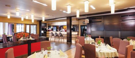 A restaurant with round tables, chairs, and a bar area.