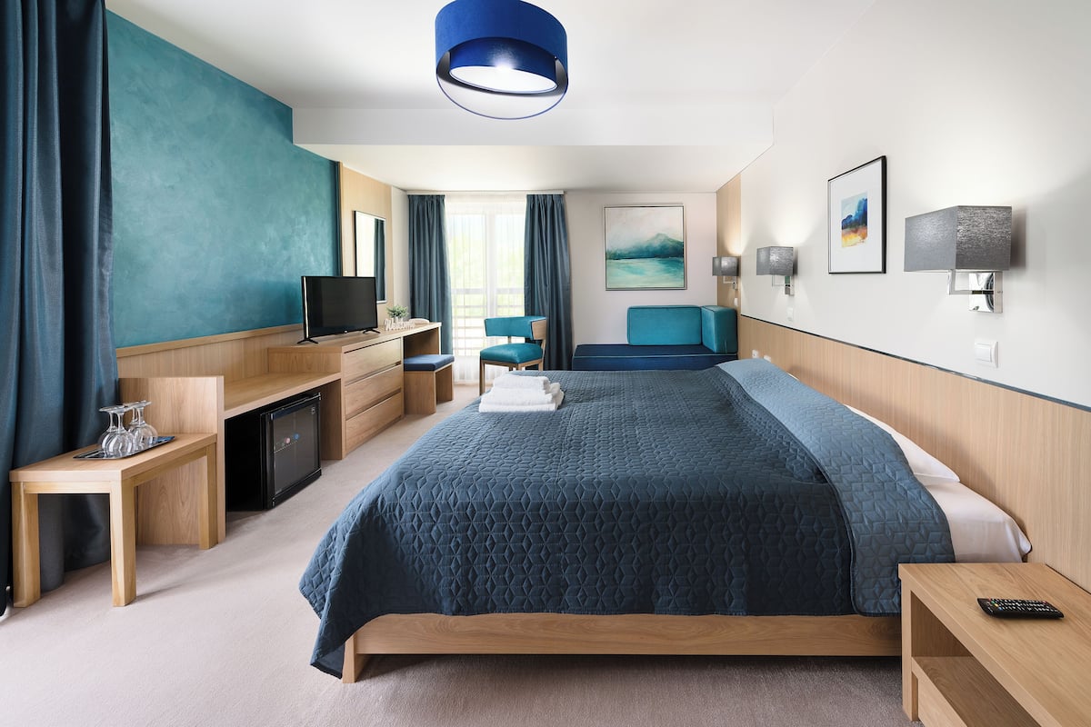 Een moderne hotelkamer met een groot bed, een bureau, een televisie en een zithoek.