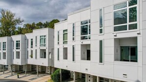 Un edificio moderno con fachada blanca y limpia, múltiples ventanas y techo plano.