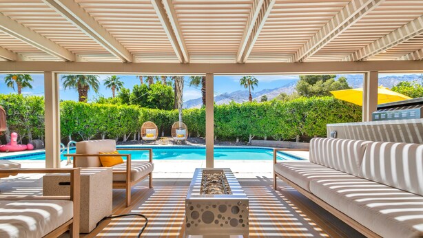 Zona junto a la piscina con un sofá, una silla y una mesa.