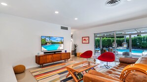 Una sala de estar moderna con un televisor de pantalla plana grande, un sofá, una mesa de centro y una silla roja.