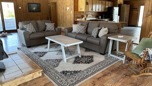 A cozy cabin interior with two sofas, a coffee table, a dining table, and a kitchen area. - Short Drive to Trails, Secluded in the Hiawatha National Forest (Wetmore)