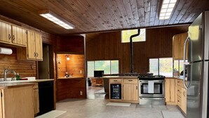 A modern kitchen with wooden cabinets, a stainless steel refrigerator, and a built-in oven. - Short Drive to Trails, Secluded in the Hiawatha National Forest (Wetmore)
