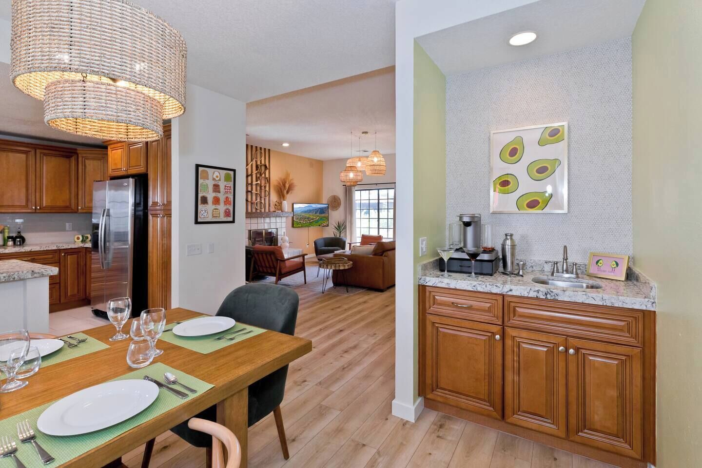 A modern kitchen with wooden cabinets, a stainless steel refrigerator, and a dining area with a wooden table and chairs.