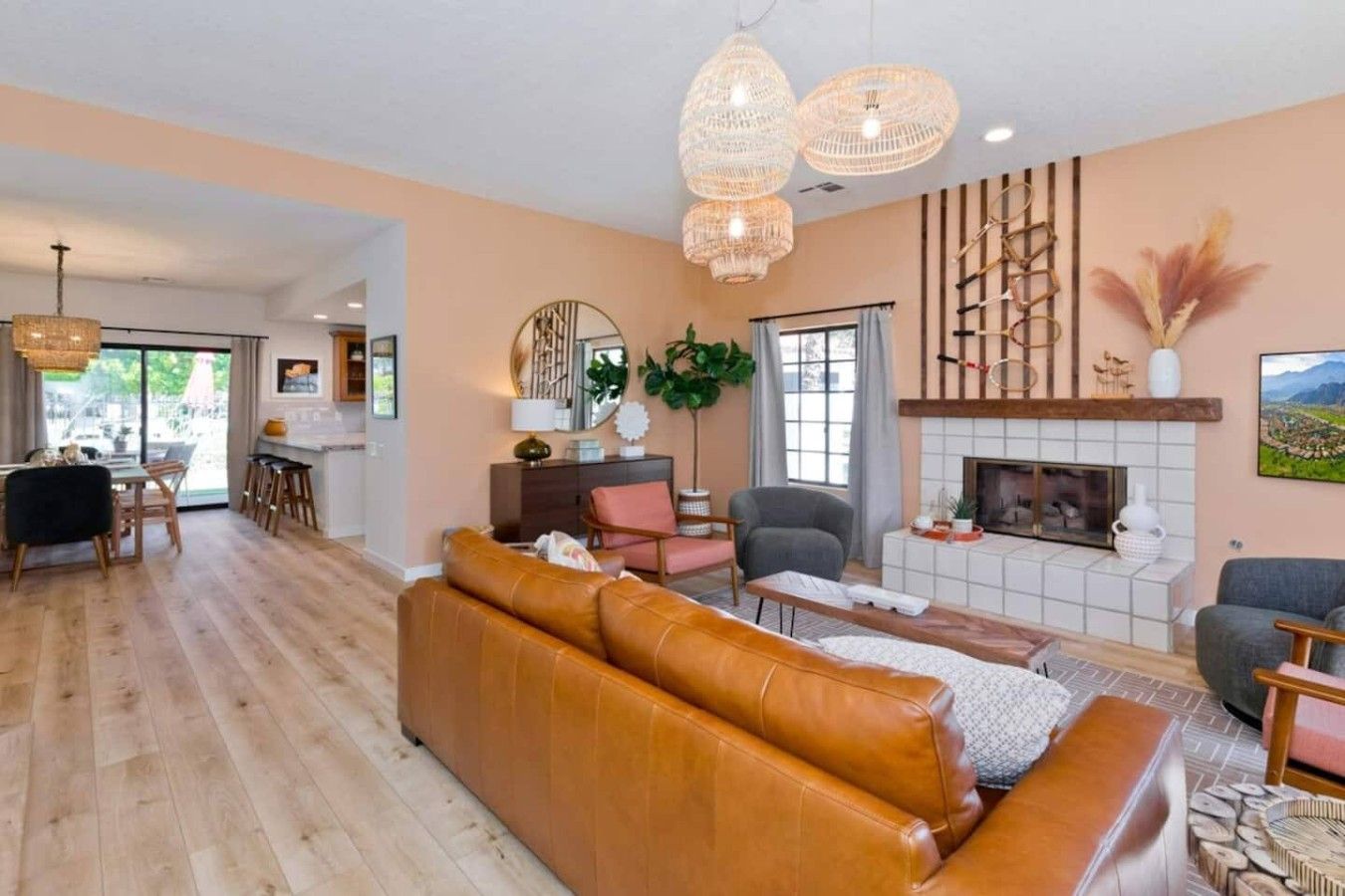A spacious living room with a leather sofa, a fireplace, and a dining area with a table and chairs.