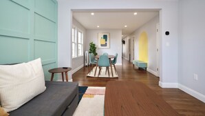A modern living room with a sofa, a dining table with chairs, and a wooden bench. - Luke 2 House, Stylish, Boston, Parking, Sleeps 8, Memorable  (Everett)