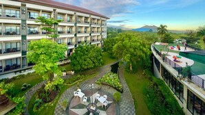 A multi-story hotel with outdoor seating areas, a pool, and a view of distant mountains. - The Green Peak, ARTOTEL Curated (Megamendung)