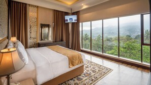A hotel room with a large bed, a TV on the wall, and a view of the mountains. - The Green Peak, ARTOTEL Curated (Megamendung)