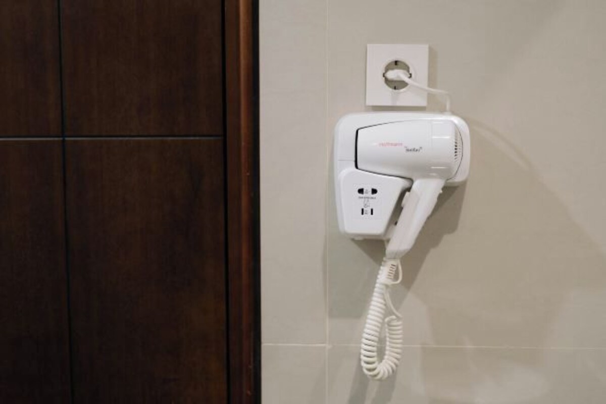 A hairdryer mounted on a wall with a power outlet and a plug.