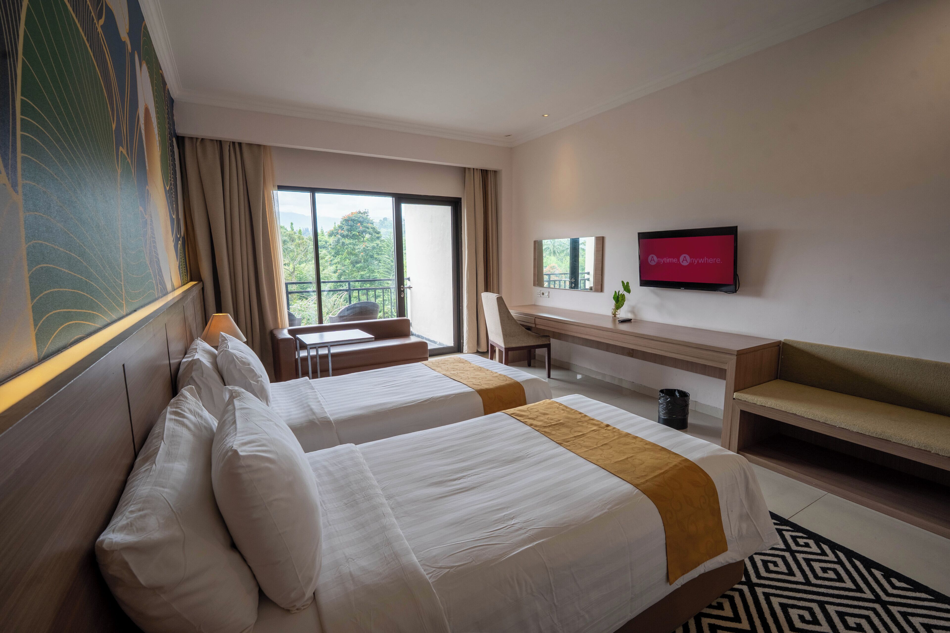 Habitación de hotel con dos camas, un escritorio, una silla, un televisor y un balcón con vistas.